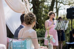 Officiante de cérémonie laïque célébrant le mariage au micro face aux mariés assis au Moulin de Bully