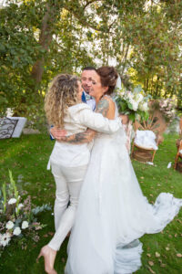 Lætitia Goux enlaçant chaleureusement la mariée et le marié à la fin de la cérémonie laïque