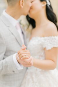 Gros plan sur la bague de mariage et baiser flou des mariés au Château de Courtomer
