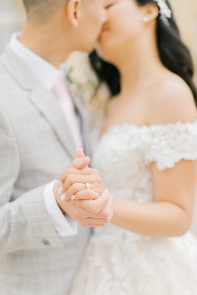 Gros plan sur la bague de mariage et baiser flou des mariés au Château de Courtomer