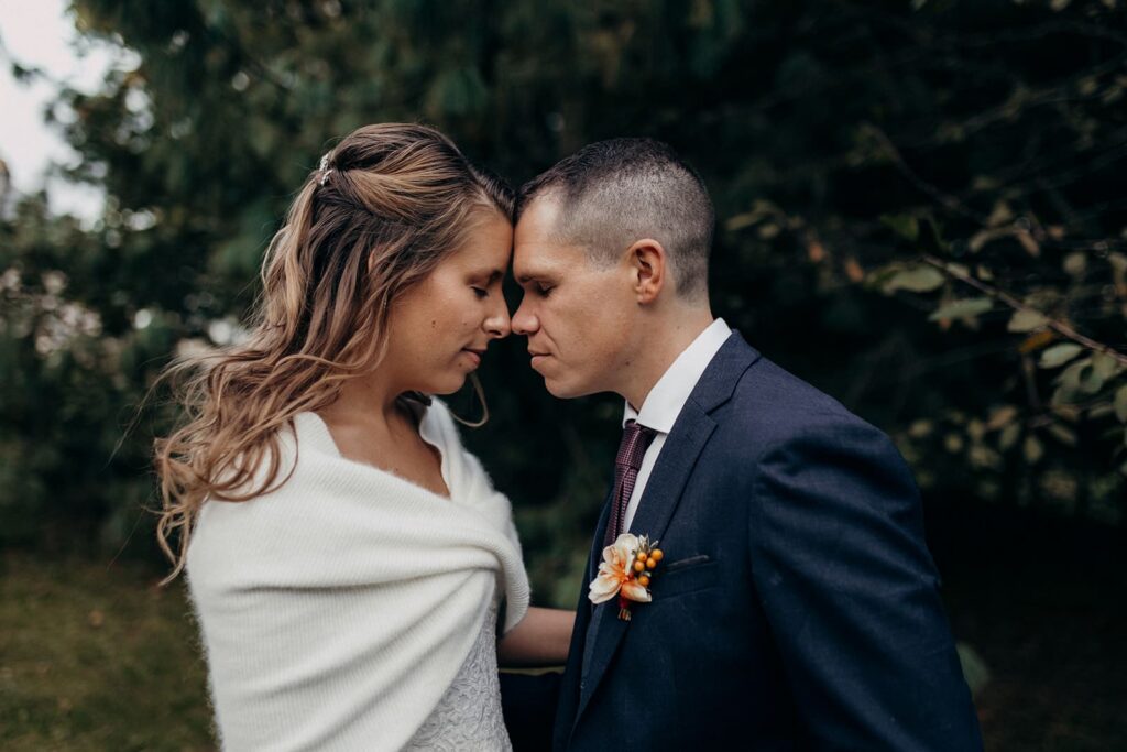 Portrait intime des mariés front contre front emmitouflés pour leur mariage d'automne en Normandie